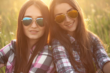 Two beautiful girls outdoors under the light of sunset. Close up. Shallow depth of field