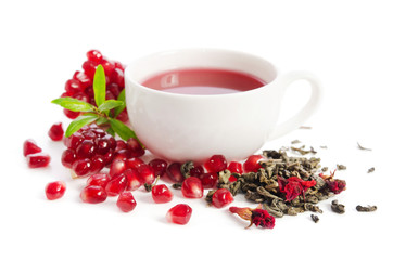 Parts of a pomegranate with pomegranate seeds and leaves, flowers, dry tea of carcade and full cup of tea isolated on white background