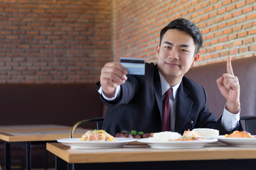 Businessman holding credit card for pay food at resterunt.
