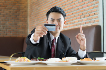 Businessman holding credit card for pay food at resterunt.