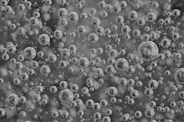 Black-and-white background with big and small grey bubbles inside a gray liquid.