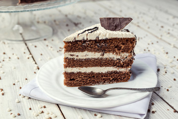dark chocolate vegan cake with cream on wooden background
