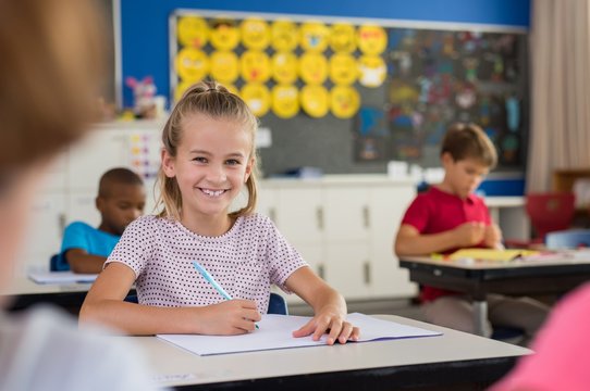 Smiling school girl taking notes