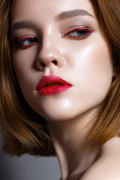 Young girl with red lips and red arrows in front of eyes. Beautiful model with makeup nude and shining skin. Photo taken in the studio. Beauty of the face. Female portrait. 