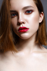 Young girl with red lips and red arrows in front of eyes. Beautiful model with makeup nude and shining skin. Photo taken in the studio. Beauty of the face. Female portrait. 