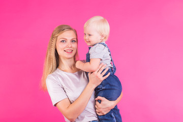 young mother and daughter having fun together on pink background