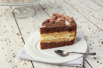 dark chocolate vegan cake with cream and caramel on wooden background