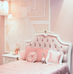 Luxury rich bedroom interior in pink color for little princess. There are different pillows on the...