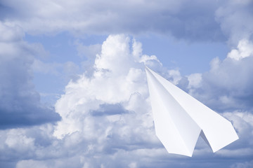 White paper airplane in a blue sky with clouds. The message symbol in the messenger