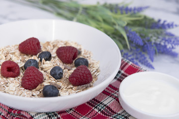 Breakfast meal of a bowl of muesli with yogurt and dried lavender in the background 
