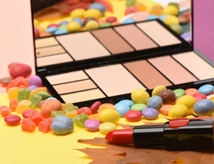 Red lipstick and palette with mirror lay on peachy, yellow