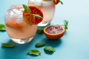 Blood orange cocktail with slices of orange on turquoise background