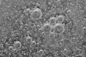 Black-and-white background with big and small grey bubbles inside a gray liquid.