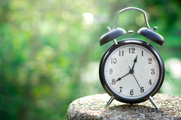 Black alarm clock on nature background with copy space
