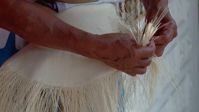 Close shot of hands weaving Panama hat in Montecristi, Ecuador