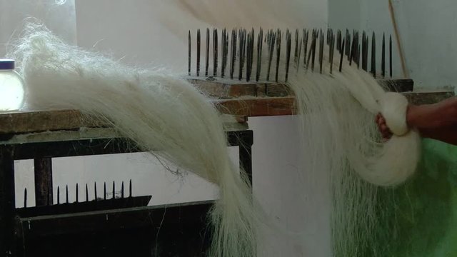 Close shot of man brushing away fibers of agave in small workshop, Montecristi