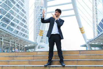 Handsome and Smart businessman standing present water bottle at stairs outdoors.