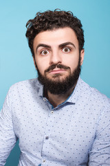 Obraz premium Shocking news. Studio portrait of a much surprised young man. The beard and blue shirt