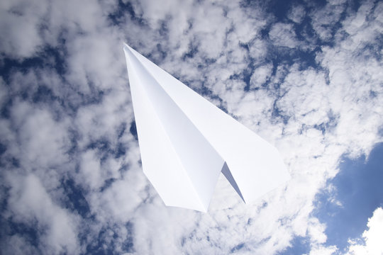 White paper airplane in a blue sky with clouds. The message symbol in the messenger