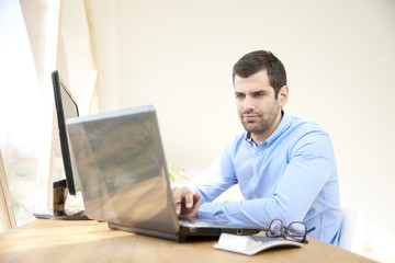 Thinking young businessman working on laptop