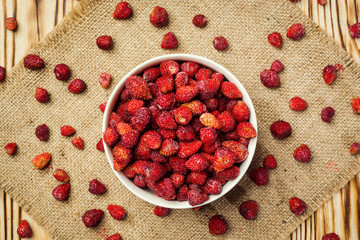 red strawberries in bowl on a wooden background