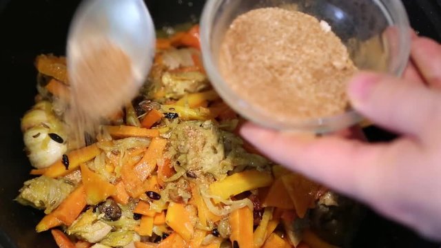 Preparation of rice dishes - pilaf from Uzbekistan. Salt and red pepper fall from the glass cup to meat and carrots.