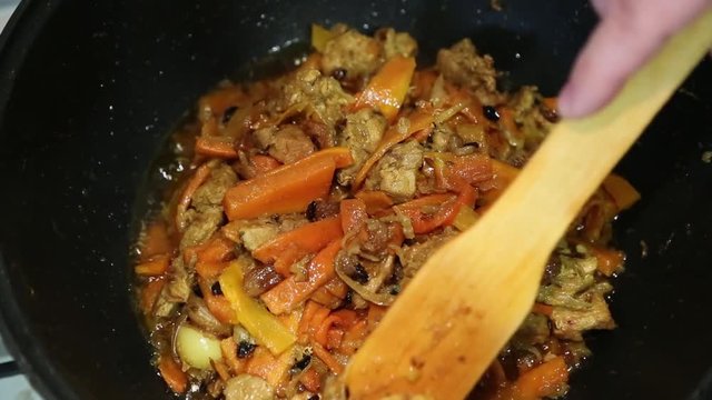 Preparation of rice dishes - pilaf from Uzbekistan. Garlic and garlic are removed from the meat and carrots on a plate.