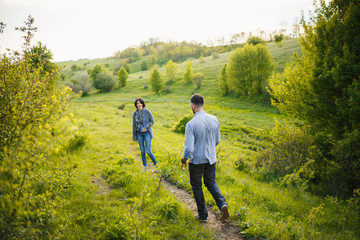 Beautiful young couple holding hands walk spring sunset countryside meadow