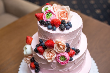 Three tiered pink wedding cake decorated with berries and flowers. Concept patisserie floristic...