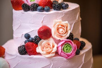 Three tiered pink wedding cake decorated with berries and flowers. Concept patisserie floristic from sugar mastic