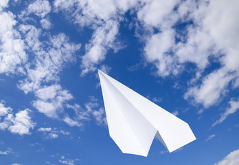 White paper airplane in a blue sky with clouds. The message symbol in the messenger