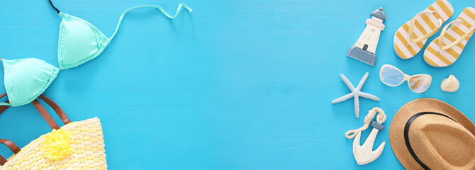 vacation and summer banner with sea life style objects and mint bikini over blue wooden background.