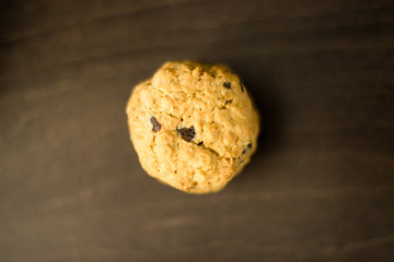 Top view of tasty homemade oatmeal cookie with chocolate drops. Brown oatcake on dark wooden table, healthy sweet home-baked products