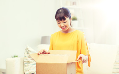 Fototapeta na wymiar people, delivery, commerce, shipping and shopping concept - happy asian young woman with cardboard parcel box at home