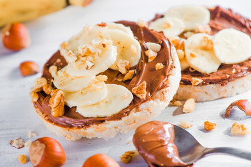 Crisp bread banana and chocolate snack. Healthy breakfast with hazel nuts. High key diet concept.