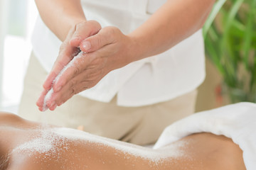 Woman enjoying getting a salt scrub beauty treatment at spa.