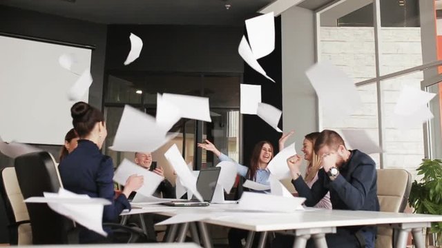 Group of business people throwing documents in air