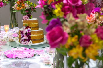 Delicious beautiful wedding cake with white cream decorated with pink and red roses and eucalyptus. Vertical