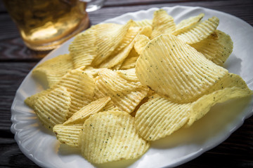 Potato chips and beer on a wooden table 