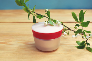 jar of cream and a branch with apricot flowers