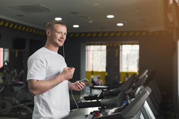 Young sporty man on treadmill in fitness club