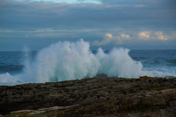 Fototapeta na wymiar Blue waves breaking over rocks