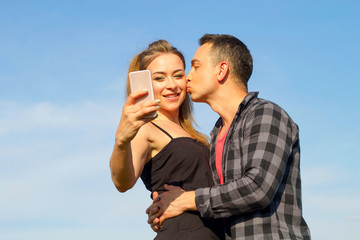 Two Young beautiful man and woman in casual clothes making selfie over blue sky