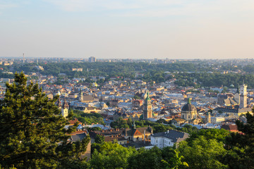 Panoramic view on the old beautiful european city. Medieval architecture with churches, houses, cathedrals and roofs. Summer green photos of ancient Lviv. Amazing town scenery in evening sunset lights