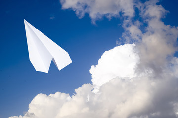 White paper airplane in a blue sky with clouds. The message symbol in the messenger