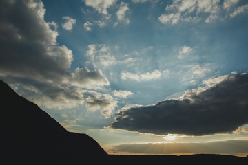 Obraz premium Amazing evening sky clouds and sun lights. Landscape of sunset in the mountains. Beautiful sunrise on the nature.
