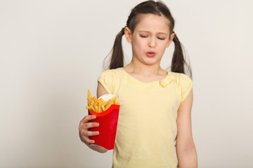 Disgusted little girl holding a bag of fries