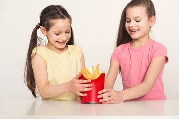 Happy little girls holding a bag of fries