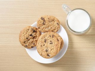 Chocolate chip cookies with milk on wooden table
