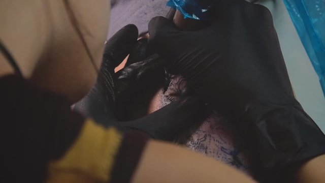 tattoo artist tattooing a tattoo of a lion, detail on the tattoo machine needle, slow motion